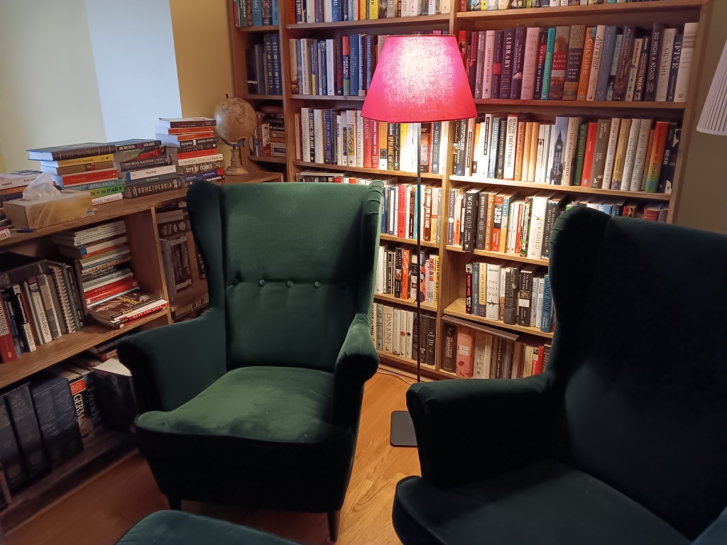 two reading chairs in front of full bookcases and a lamp
